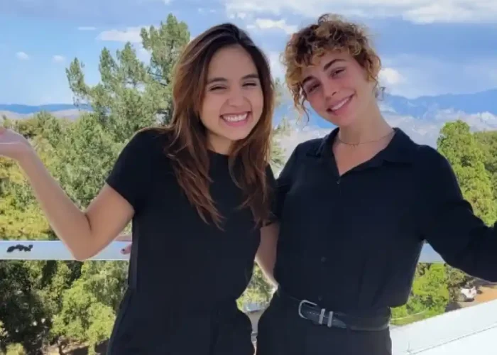 Two Premier Staff team members in black attire standing together on a terrace with a scenic background of trees and mountains.