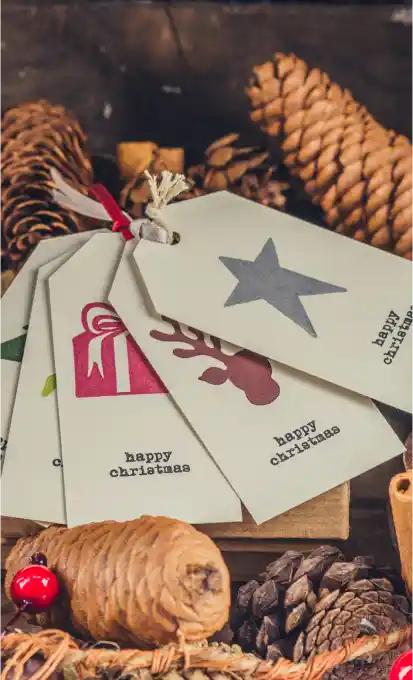 Premier Staff team creating a festive holiday atmosphere, with a beautifully arranged display of Christmas-themed gift tags, pinecones, cinnamon sticks, and red berries, highlighting their attention to detail and creativity in event decoration.
