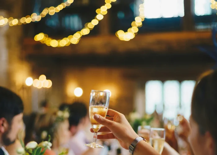 Premier Staff team members and guests raising glasses in a celebratory toast at a festively decorated event with string lights and floral arrangements.